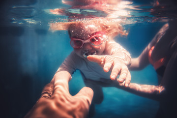 Happy child toddler fun swimming underwater with parents during summer beach holidays vacation