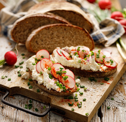 Sandwiches made of sourdough bread with the addition of curd cheese, fresh radishes and scallion on...