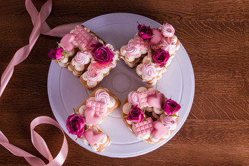 The hands of the confectioner with a delicate and delicious cake of letters. Cake with live flowers, white chocolate, beas. Hands of a pastry chef, packing dessert.