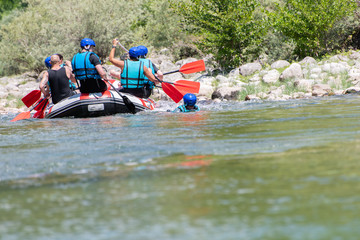Rafting team goes down the river on the beautiful sunny day. Back view.