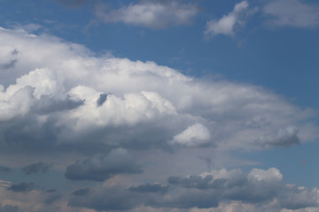 The sun shines through the cumulus clouds in the blue sky. Background and texture for artists and design. Bright light in the eyes. Water in gaseous state. The circulation of fluid in nature