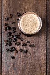 Coffee foam in a cup of coffee on a wooden background with coffee beans