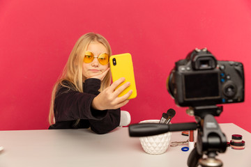 Happy girl at home speaking in front of camera for vlog. Teenage kid working as blogger, recording video tutorial for Internet