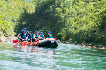 Rafting team goes down the river on the beautiful sunny day.