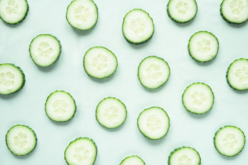 Pattern with freshly cut cucumber slices on green background