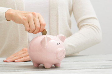 woman hand putting money coin into piggy for saving money wealth and financial concept