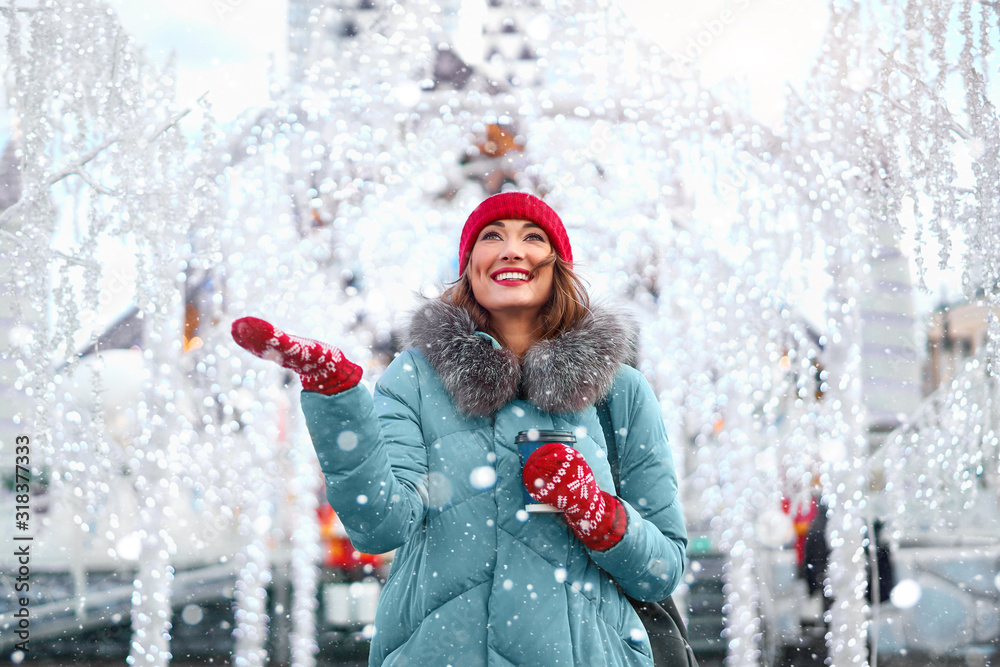 Wall mural beautiful lovely middle-aged girl with curly hair warm winter jackets stands ice rink background tow