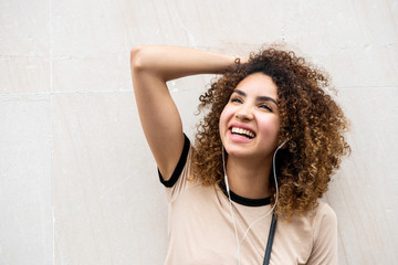 Close up beautiful young african american woman with curly hair smiling listening to music with earphones