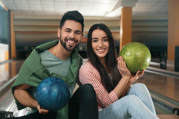Fototapeta premium Happy young couple with balls in bowling club