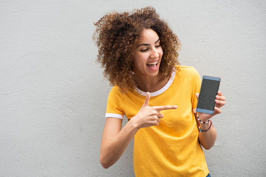 Close up happy young woman pointing finger to mobile phone screen