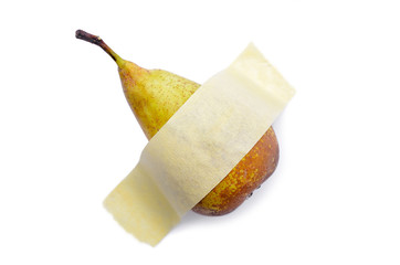 Pear glued with yellow tape to a white surface. Modern pop-art.