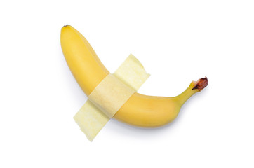 A banana glued with yellow tape to a white surface. Modern pop-art.