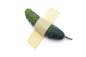 Cucumber glued with yellow tape to a white surface. Modern pop-art.