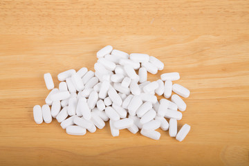 Fototapeta na wymiar Many prescription, vitamin or supplement pills on a wood table