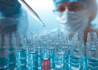 A drop is dripping from a pipette into a test tube. Laboratory research. 