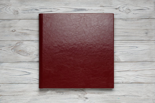 Family Red Photo Book With  Leather Cover Close Up . Photoalbum With A Hard Cover On A Wooden Background. Wedding Red Photo Album Isolated. Burgundy Photo Album With Copy Space For Text