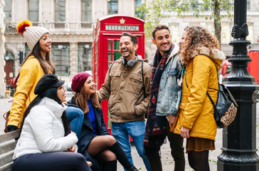 A group of young friends talk and laugh happily in a London street