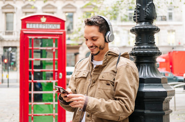 A boy listens to music with headphones and uses the mobile phone in a London street