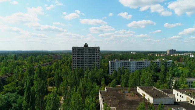 Aerial view of abandoned buildings and streets overgrown with trees in city Pripyat near Chernobyl nuclear power plant. Exclusion Zone. Camera approaching. Sign of USSR on the roof. 4K drone footage.
