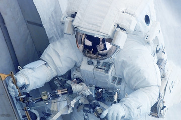 An astronaut in a spacesuit is engaged in research. Elements of this image were furnished by NASA.