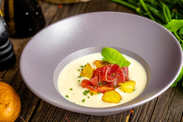 rustic wooden background, top and side, on a plate, white cream soup of smoked potato, with beef...