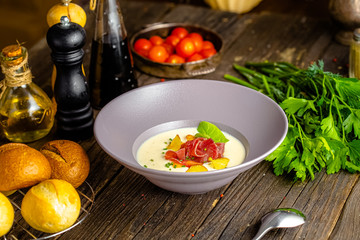 rustic wooden background, top and side, on a plate, white cream soup of smoked potato, with beef...
