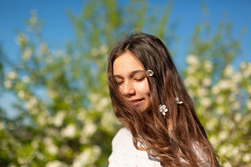 Portrait of a young beautiful teenager girl in a blooming spring green garden