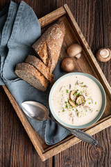Delicious lunch, comforting Cream of mushroom soup topped with freshly chopped chives, served with crusty bread