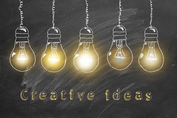 Fototapeta na wymiar Row of flickering tungsten light bulbs drawn in chalk on a blackboard. Creative ideas concept