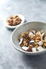 Bowl of granola with nuts, cranberry and cocoanut. Concept for a tasty and healthy meal. Stone background. Close up. 