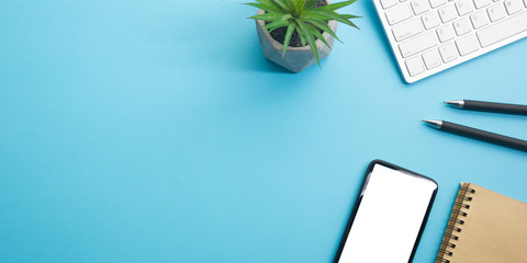 Blue desk office with laptop, smartphone and other work supplies with cup of coffee. Top view with...