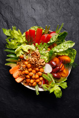 Buddha bowl, healthy salad with various vegetables, seeds and herbs on a black background, top view. The concept of healthy eating