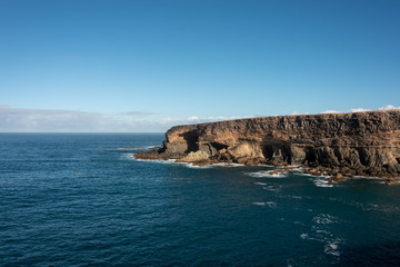 Fototapeta na wymiar Cliffs by the ocean under blue sky. Ajuy, Fuerteventura. 