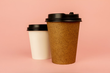 Paper coffee cup ant tea cup on colored pink background. Coffee to go containers with lids, blank space for logo. Mockup.