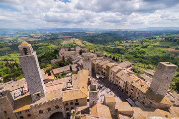 Fototapeta na wymiar cityscape panoramic of san gimignano with small town brick houses and tower torre grossa big tower and piazza cisterna with water well in tuscany in italy sky with clouds