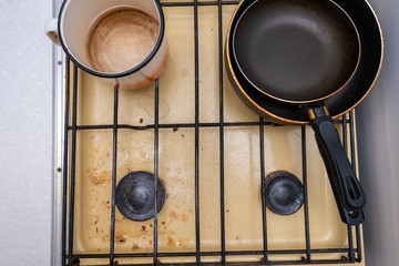 Dirty unhygienic surface of kitchen gas stove with grease and soot stains with kitchenware pans on it