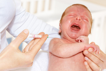 Baby infant boy cry during vaccination with nurse hold syringe near arm