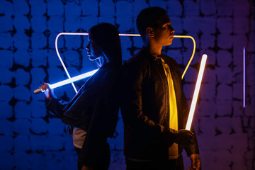 Young couple with neon lamps on dark color background