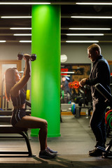 Fototapeta na wymiar Girl doing exercises in the gym with a trainer