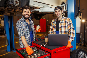 portrait of two smiling specialists working on laptop computer and looking at the camera in the...