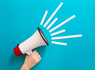 Female hand with megaphone on color background