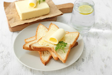 Plate with slices of bread and fresh butter on white background