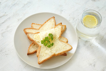 Plate with slices of bread and fresh butter on white background
