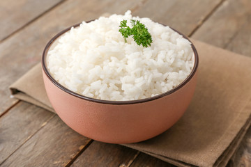 Boiled rice in bowl on wooden table