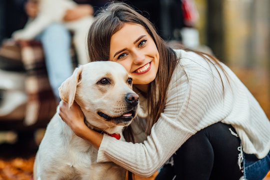 Cute woman hugging her golden retriver labrador in the park.