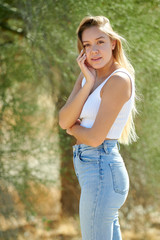 Beautiful young Latina woman posing in desert wearing white tank top and jeans