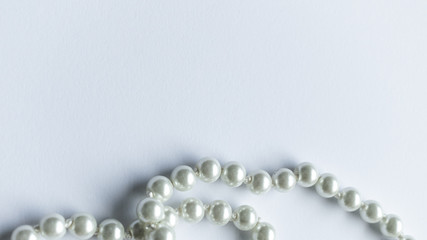 White pearls necklace on white background, clean and tidy picture, shiny pearl, close view and lots of negative space