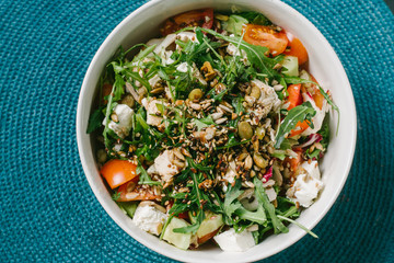 Diet menu. Healthy salad of fresh vegetables - tomatoes, avocado, arugula, radish and seeds on a bowl. Vegan food