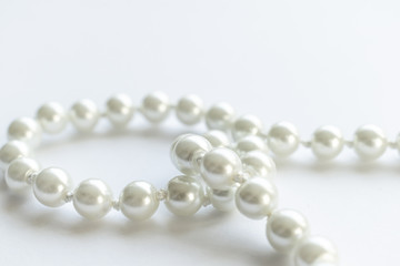 White pearls necklace on white background, clean and tidy picture, shiny pearl, close view and lots of negative space