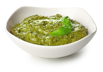 Bowl of tasty pesto sauce on white background
